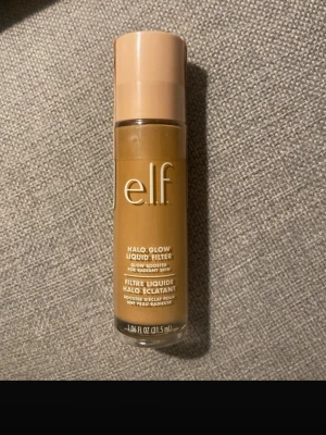 e.l.f. Halo Glow Liquid Filter - e.l.f. Halo Glow Liquid Filter är en flytande glow booster som ger huden en strålande finish. Kommer i en glasflaska med beige lock och har en varm, gyllenbrun ton. Perfekt för att skapa en naturlig lyster och kan användas ensam eller under foundation.
