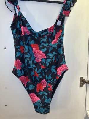 Blommig baddräkt från Motel - Säljer en snygg baddräkt från Motel. Axelbanden har volangdetaljer.