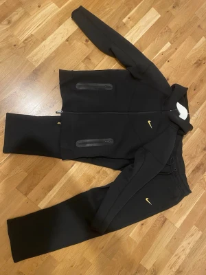 Svart Nike dunväst med dragkedja - Säljer en nike nocta trackusit, jag vill sälha den för att jag vill köpa en annan förg. Storlek M men passar också storlek S