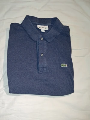 Blå Lacoste slim fit pikétröja - Säljer en Lacoste Piké slim fit i storlek S. Är använd några gånger, men är fortfarande I bra skick. Säljer pga att den är för liten. Nypris är 1350kr. Jag säljer för 350kr. Pris kan diskuteras.