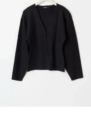 Svart kofta med knappar från Ginatricot - Säljer en svart kofta från Ginatricot med v-ringning och snygga knappar framtill. Koftan är långärmad och har en klassisk, enkel design som passar till det mesta. Perfekt för lager på lager och chill vardagsstil.