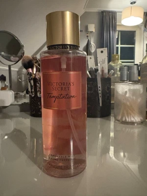 Victoria's Secret Temptation Mist - Fräsch body mist med noter av äpple och ökenblomma. Volym: 250 ml. Ingredienser inkluderar vatten, propylenglykol, glycerin, parfym, ricinolja, och flera doftämnen. Tillverkad i USA. Perfekt för dig som vill sticka ut!