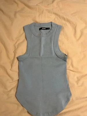 Ljusblå ärmlös linnetopp Bik Bok - Säljer en ljusblå ärmlös linnetopp från Bik Bok i storlek XS. Toppen har rund halsringning och är tillverkad i mjuk bomull, perfekt för varma dagar eller som layering-plagg. Enkel och stilren design som passar till mycket.