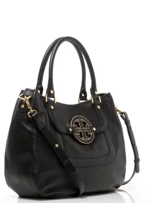 Svart skinnväska från Tory Burch - Snygg svart handväska från Tory Burch i äkta läder med guldfärgade metalldetaljer och stort logospänne framtill. Väskan har handtag samt flera innerfack. Perfekt för dig som vill ha en klassisk och stilren väska med plats för allt. Väskan är väl bevarad