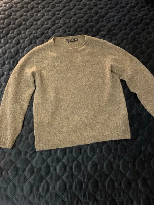 Grå stickad tröja Polo Ralph Lauren - Mysig grå stickad tröja från Polo Ralph Lauren, tillverkad i Skottland. Tröjan är i en klassisk modell med rund hals och ribbade muddar. Materialet består av 89% ull och 11% kashmir vilket gör den extra mjuk och varm .Jag tar gärna byten i Stockholm 