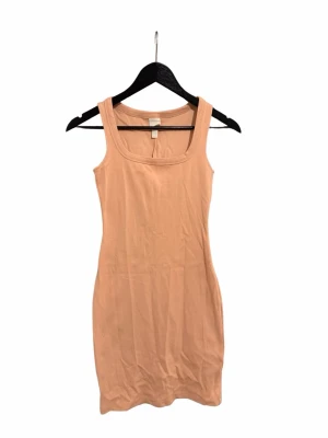 Beige ärmlös kortklänning - Säljer en enkel och stilren beige kortklänning med breda axelband och rundad urringning. Klänningen är figurnära och tillverkad i mjuk bomull.