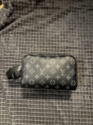 Louis Vuitton svart monogram axelväska - Säljer en svart axelväska från Louis Vuitton med klassiskt monogrammönster i grått. Väskan har en rektangulär form, justerbart handtag och dragkedja i silver. Tillverkad i skinn med detaljer i metall. Perfekt för dig som vill ha en stilren och ikonisk accessoar. Split tandkräm i den där av priset.