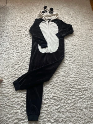  onepiece panda  - Bilden visar ingen väst utan en panda-inspirerad onesie med huva och dragkedja framtill.
