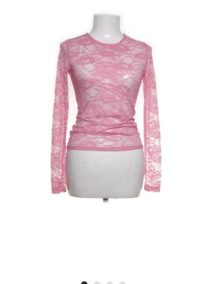 Rosa spetsblus med lång ärm - Säljer en transparent rosa blus i spets med lång ärm och rund halsringning. Blusen har ett figurnära snitt och är perfekt för dig som vill ha en feminin och trendig look. Materialet är mjukt och stretchigt för extra komfort. Vet dock ej storleken men tror xs elelr xxs
