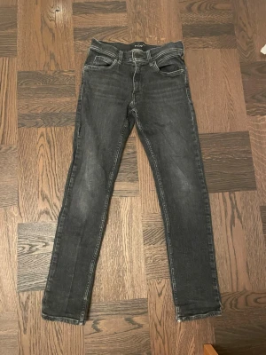 Replay svarta skinny jeans - Säljer ett par svarta Replay jeans med skinny passform och klassisk femficksdesign. Jeansen har en något tvättad look och tydliga sömmar. Materialet är jeans och de har normal midja. Perfekta för dig som gillar en smal siluett och stilren vibe.