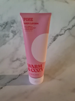 PINK Warm & Cozy Body Lotion 236ml - PINK Warm & Cozy Body Lotion med doft av mjuk vanilj, rostad kokos och passionsfrukt. Kommer i en rosa tub på 236 ml med vit kork. Vegansk formula, fri från artificiella färgämnen och godkänd av dermatolog. Ger 24h återfuktning och är ej testad på djur. Helt ny och oanvänd