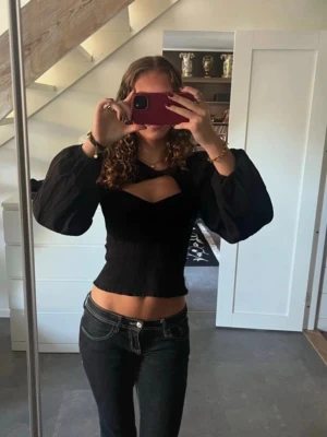 Svart blus med ballongärmar  - Säljer en svart blus från Envii med croppad passform och ballongärmar. Toppen har en snygg cut-out detalj vid bröstet och är tillverkad i ett lätt, strukturerat material. 🩷