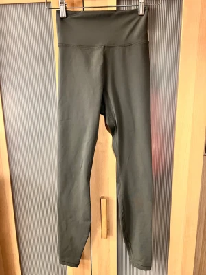 Mörkgröna tränings leggings från H&M Move XS - Snygga mörkgröna leggings från H&M Move i storlek XS. Tillverkade i ett stretchigt och mjukt syntetmaterial med hög midja och smal passform. Perfekta för träning eller chill dagar. Snygga sömmar och enkel design utan fickor eller mönster.
