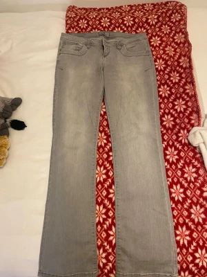 Ljusgrå bootcut jeans - Snygga ljusgrå jeans med klassisk femficksdesign och bootcut-ben. Jeansen har en normal passform och är tillverkade i mjukt denimtyg. Baksidan har stilrena fickor med dekorativa sömmar. Perfekt för dig som gillar en enkel och clean look. Storlek 29/32, finns defekter men jag tror att fläckarna kan gå bort! 