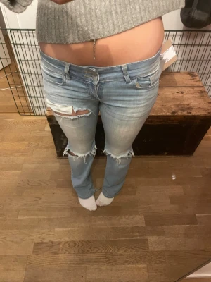 Ljusblå bootcut jeans med slitningar - Säljer ett par ljusblå jeans med bootcut passform och låg midja som jag köpte här på Plick. Byxorna har slitna detaljer och revor vid knäna och låren, Dom är väldigt slitna mellan benen som man kan se på en av bilderna därav kan pris diskuteras, innerbenslängd 83cm 💗💗
