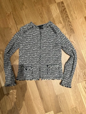 Marin/vit  cardigan jacka från Massimo Dutti Stl XS - Snygg cardigan jacka från Massimo Dutti i italienskt garn, tillverkad i Spanien. Jackan är vit och mörkblå med rutig stickad struktur, har dragkedja framtill, två fickor och fransade kanter. Långärmad och perfekt för dig som gillar en chill och trendig look.