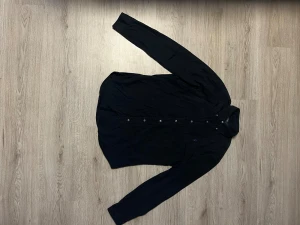 Svart slim fit skjorta Polo Ralph Lauren - Svart skjorta från Polo Ralph Lauren i slim fit med klassisk krage och knappar hela vägen. Långärmad och tillverkad i mjuk bomull. På bröstet finns den ikoniska lila broderade Polo-loggan som ger en snygg kontrast. Perfekt för dig som gillar stilrena och enkla plagg.