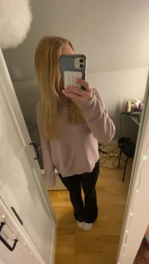 Ljusrosa stickad tröja med rund hals - Mysig ljusrosa stickad tröja med rund hals och ribbade muddar vid ärmslut och nederkant. Tröjan har en loose passform och långa ärmar, perfekt för att hålla sig varm under kyliga dagar. Enkel och stilren design som är lätt att matcha.