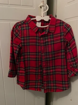 Röd rutig skjorta från H&M - Klassisk röd rutig skjorta från H&M med svarta och vita detaljer. Skjortan har långa ärmar, knappar framtill och mjukt bomullsmaterial. Perfekt för en avslappnad och cool stil.