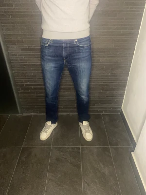 Levi's 511 blå jeans W33 L34 - Snygga Levi's 511 jeans i klassisk blå tvätt med lätt slitning. Modellen har en slim passform och raka ben, med fem fickor och gul kontrastsöm. Perfekt för dig som gillar en modern och stilren look. Jeansmaterialet är slitstarkt och bekvämt.