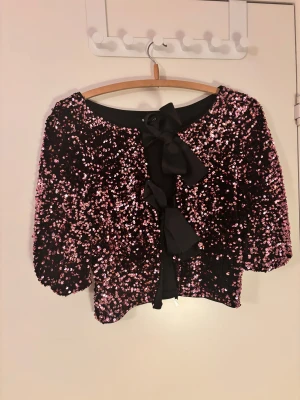Glittrig svart kofta med rosett Gina Tricot - Jättefin glittrig topp från Gina. Köpt förra året och endast använd en gång. Hör av dig vid frågor!💕