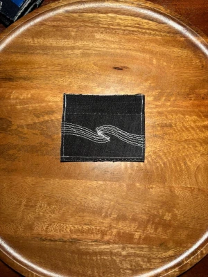 Svart R’essentials korthållare med Nudie brodering - Stilren och hållbar svart denim korthållare med Nudie Jeans brodering. Egendesignad och egen tillverkad av 100% autentiskt material. Skriv för mer bilder eller övriga funderingar.