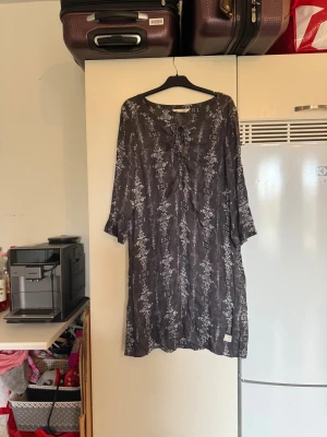 Mörkgrå mönstrad klänning Odd Molly - Snygg mörkgrå kortklänning från Odd Molly med vitt mönster och snörning vid halsen. Klänningen har trekvartsärmar och är tillverkad i ett lätt och skönt material. Perfekt för dig som gillar bohemisk och avslappnad stil. Från märket Odd Molly. Storlek 3 som enligt deras storleksguide motsvarar en L. Mycket fint skick, jag hittar inga synliga anmärkningar eller defekter. 