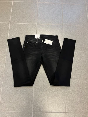 Svarta slimmade jeans från tiger of sweden  W29 L34 - Svarta jeans från Tiger of sweden passform och smala ben. Klassisk femficksmodell med diskret tvättade detaljer och normal midja. Perfekta för dig som gillar en slimmad look och vill ha ett par stilrena jeans i garderoben.