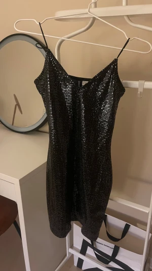 Svart glittrig kort klänning med paljetter - Nyårsklänningar 🎉🎉Den härligt glittrande ärmlösa är i  storlek S. Supersnygg svart kort klänning i storlek M från Gina Tricot med tunna axelband och glittriga paljetter över hela klänningen. Perfekt för dig som vill sticka ut med en festlig look. Sitter tight och har en feminin siluett. Jag skickar samma vardag om du köpt dem!! Men senast kl 19:00 och helger senast 16:00 klänningarna. 