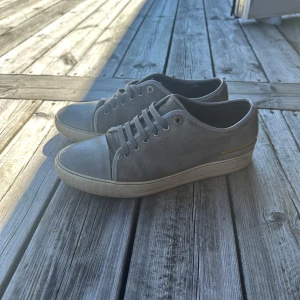 Lanvin skor Steal  - Snygga grå sneakers från Lanvin med ovandel i mocka och tåparti i slätare material.Storlek 41 men passar mer 42. Skorna har rund tå, platt sula och klassisk snörning. Perfekta för dig som gillar stilrena och minimalistiska sneakers med exklusiv känsla.Ej box.