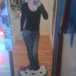 Svart långärmad v-ringad topp - Säljer en svart långärmad topp med v-ringning och slim passform. Toppen är enkel och stilren, perfekt att matcha med jeans eller kjol. Materialet känns mjukt och stretchigt, vilket gör den skön att bära hela dagen. Passar dig som gillar en klassisk look.