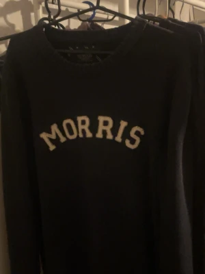Mörkblå stickad tröja från Morris - Snygg mörkblå stickad tröja från Morris med vit broderad logga över bröstet. Klassisk rund halsringning och långa ärmar. Perfekt för dig som gillar stilren och tidlös design med en sportig touch. Storlek L men passar även M jättebra. Vid fler frågor är det bara att höra av sig.