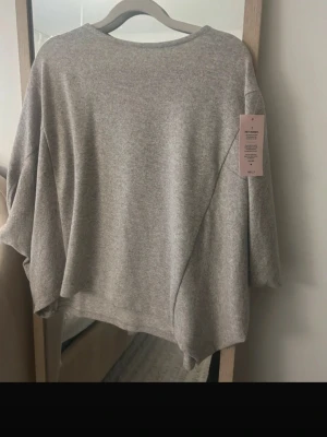 Grå oversized tröja från Nelly XS - Supermjuk och oversized grå tröja från nelly i storlek XS. Tröjan har en avslappnad passform med breda ärmar och rund halsringning. Perfekt för lager-på-lager och chill dagar.