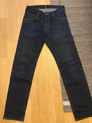 Lee Daren Zip Fly jeans mörkblå W29 L32 - Säljer ett par klassiska Lee Daren Zip Fly jeans i mörkblå tvätt. Jeansen har rak passform, fem fickor och dragkedjegylf. Tillverkade i slitstarkt denimtyg av bomull. Perfekta för dig som gillar en tidlös och clean look.