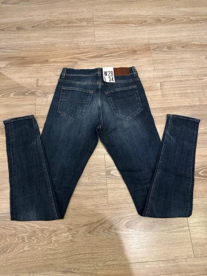 Tiger of Sweden  - Mörkblå tiger of Sweden 511 jeans med skinny passform och klassisk femficksdesign. Jeansen har subtila slitningar och snygg tvätt, tillverkade i stretchig denim för extra komfort. Perfekta för dig som gillar en smal siluett och stilren look.