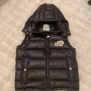 Svart double badge vest från Moncler - Double badge moncler vest, väldigt bra Scick använd  typ 2 gånger men är i topp Scick. Tyvär för liten för mig. Luvan tillkommer också.  