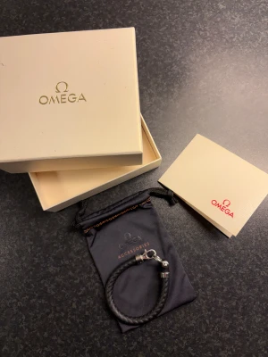 Omega armband Svart  - Svart Omega armband med tillbehörspåse och etui. STORLEK - M