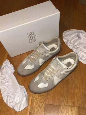 Maison Margiela Skor - Säljs eftersom dom inte används längre. Väldigt fint skick utan defekter! Storlek 43. Skick 8/10. Färg Grå/Vita. Skriv gärna vid minsta fundering!😊