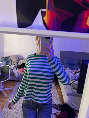 Randig grön och vit långärmad topp - Snygg långärmad topp med gröna och vita ränder. Klassisk rund halsringning och relaxed fit, perfekt att styla med jeans eller kjol. Mjuk och skön bomull, passar dig som gillar en enkel men trendig look.