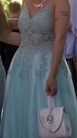 Balklänning - Lägger ut min balklänning på nytt! Den är uppsydd för mig som 155cm med cirka 6cm klackar. Även insydd lite i bröstkorgen men kan sprättas upp. Den har en djup rygg och glittrar! Tyvärr har den fått några fläckar på yttersta lagret som jag inte vet hur man får bort. Nypris ca 2.300kr. Väska på bild ingår. 