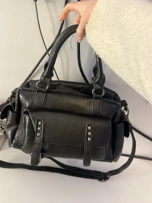 Väska  - Det är en svart väska som håller det mesta, den är i okej skick syns att den har blivit lite använd. Den har ett ställe där en knapp åkt av (la med i bilderna) vet ej vart den är ifrån och pris kan absolut diskuteras!