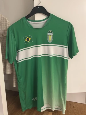 Brasiliansk fotbollströja - En grön t-shirt med brasiliansk flagga och texten 'ATLETA TRIUNFO BRASIL'