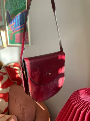 Axelremsväska i läder  - 💼 Perfekt vintageväska med patina som bara blir snyggare med tiden. Färgen är djupt mahognyeröd och skiftar lite i färg beroende på ljus. Tidlös saddlebag-modell som passar till precis allt.  ✨Se även mina andra annonser, 3 för 2 på allt! ✨