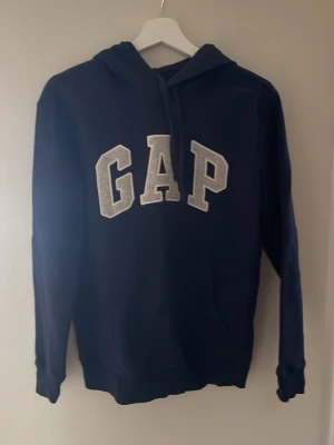 Hoodie GAP - Snygg mörkblå hoodie från GAP. Perfekt för en avslappnad och trendig stil.  Perfekt för dig mellan 170-180cm. Använd en gång. Hör av er vid frågor!