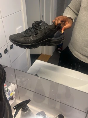 Nike Air Max svart sneaker - Säljer ett par helsvarta Nike Air Max sneakers med klassisk synlig luftdämpning i sulan. Skorna har en sportig design med mesh och syntetmaterial, samt svarta skosnören och diskret Nike-logga på sidan. Perfekta för dig som gillar stilrena och bekväma sneakers.