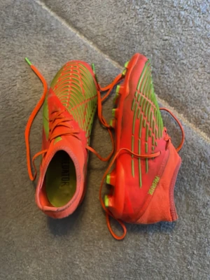 Adidas fotbollsskor  - Säljer ett par adidas fotbollsskor med gröna detaljer och snörning. Skorna har gröna dobbar och ett mönster av tunna gröna linjer på ovansidan. Tillverkade i syntetmaterial för bra grepp och kontroll på planen. Perfekta för dig som vill sticka ut på fotbollsplanen. Bra skick och är i storlek 37 och 1 tredjedel. 