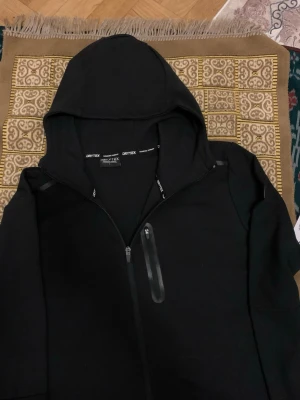 Dry Tex Tech Full Zip Hooded Jacka – Svart - ✔️ Hel dragkedja framtill ✔️ Med huva ✔️ Färg: Svart ✔️ Storlek: L ✔️ Stilren och bekväm design  #jacka #hoodie #sportjacka #träningsjacka #drytex #svartjacka #fullzip #unisex #streetwear #sportstyle #vardagskläder