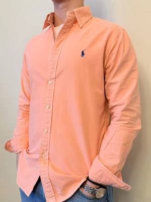 Rosa Ralph Lauren skjorta - En stilren skjorta från Ralph Lauren Second hand men i väldigt fint skick ✨ Tvättad och struken – redo att användas direkt.  Perfekt för sommaren/våren, funkar både uppklätt och casual. Inga defekter och slim fit.  Storlek 👔: M Nypris 💰: ca 1 300 kr 