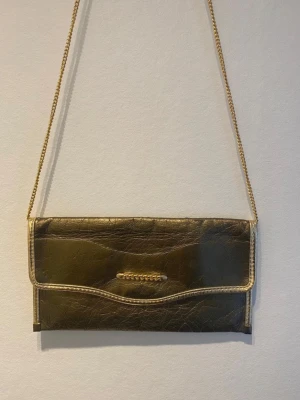 Guldig kuvertväska med kedja - Perfekt accessoar till balen eller till en night OuT! Köptes på Busfrö, därför säljer jag den för billig peng! //E
