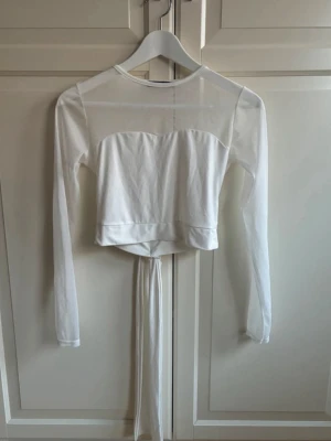 Vit topp nyskick  - Aldrig använd. Knytband som kan knytas både framtill och bak 